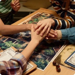Groep vrienden die hun handen op elkaar leggen tijdens een bordspel op tafel.